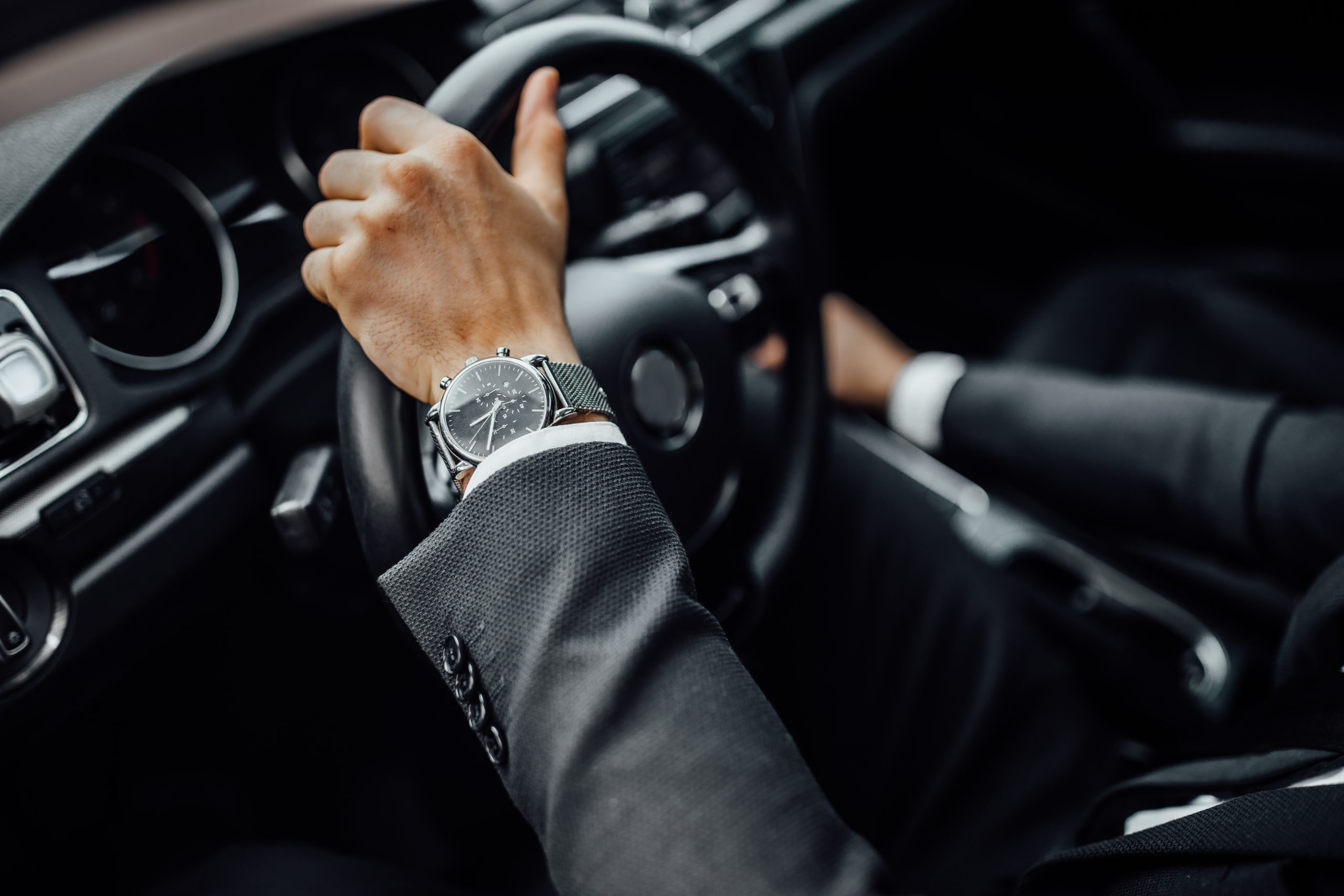 A close up of a man's hand on a luxury steering wheel.
