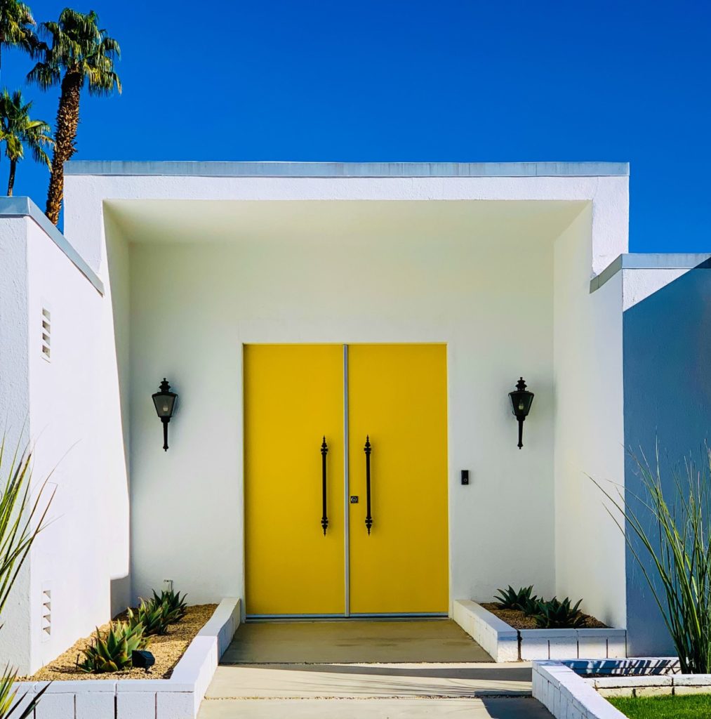 Yellow front door to a mid-century modern house.