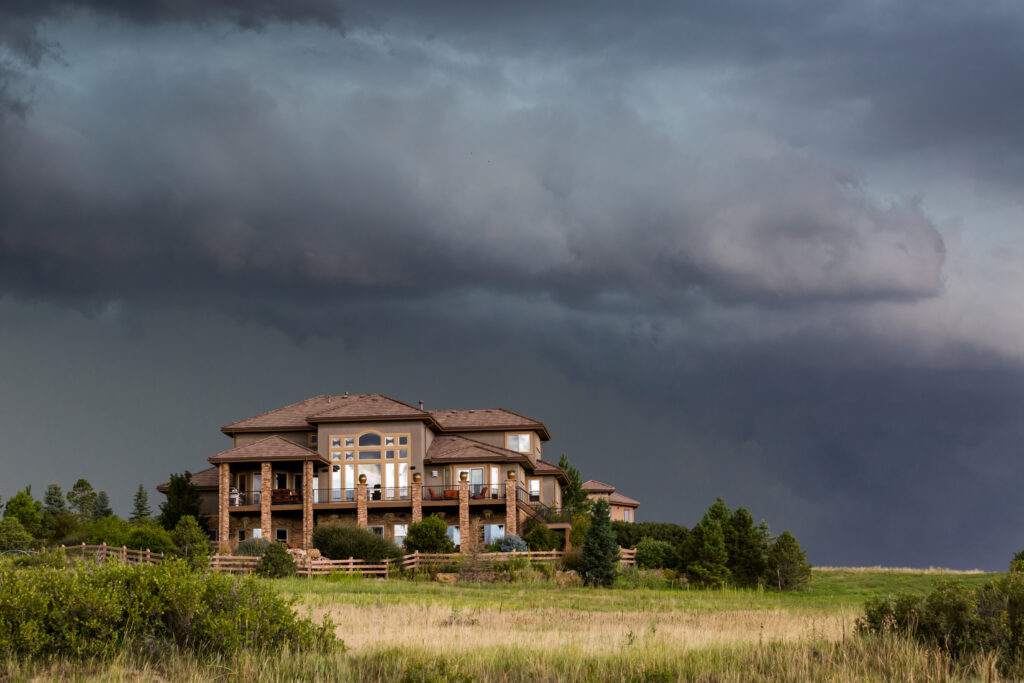 A large luxury home, with storm clouds approaching, representing insurance pullback from certain states.