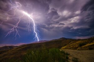 Lightning streaks across the sky, representing how billion-dollar weather disasters are upsetting the insurance market.