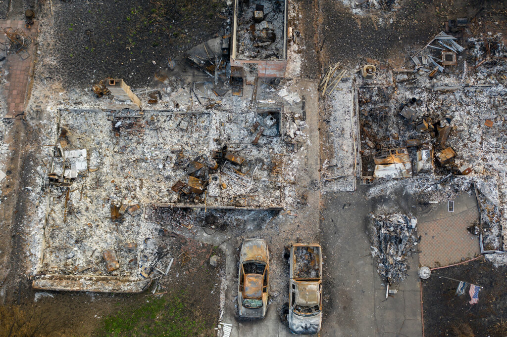 An aerial view of a burned-down community from a 2020 forest fire, representing the devastation an unprepared California FAIR plan could face.
