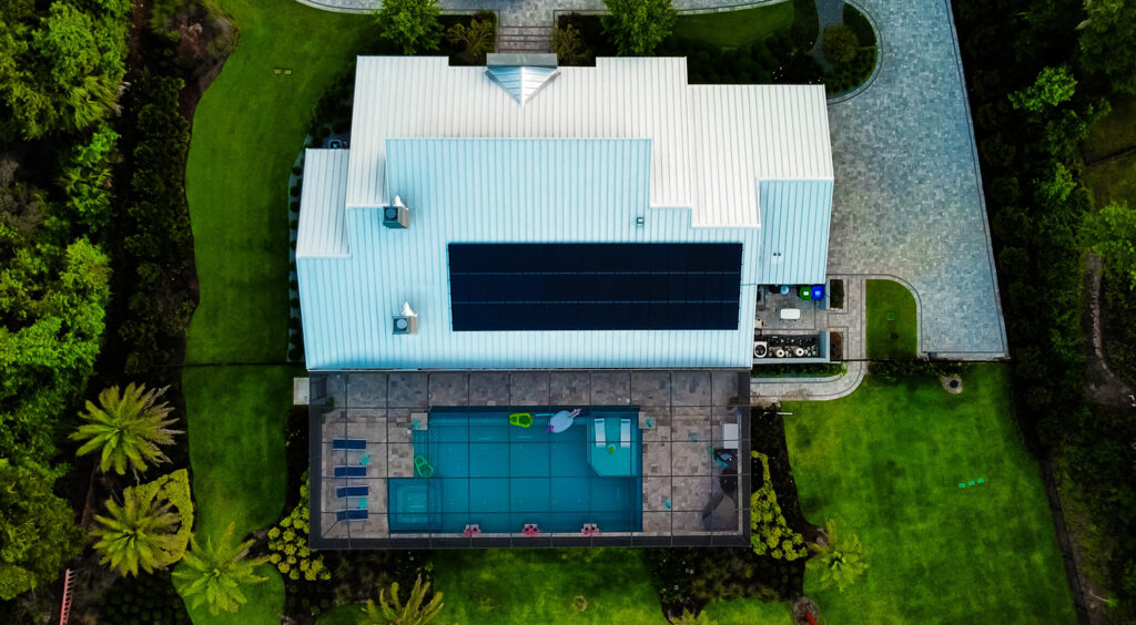 Aerial view of a modern home with solar panels and a huge pool, similar to what insurers could be using to spy on properties.