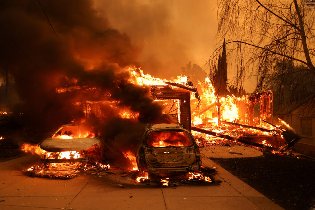 A wildfire engulfs a home and vehicle in Los Angeles, highlighting California's deepening home insurance crisis.